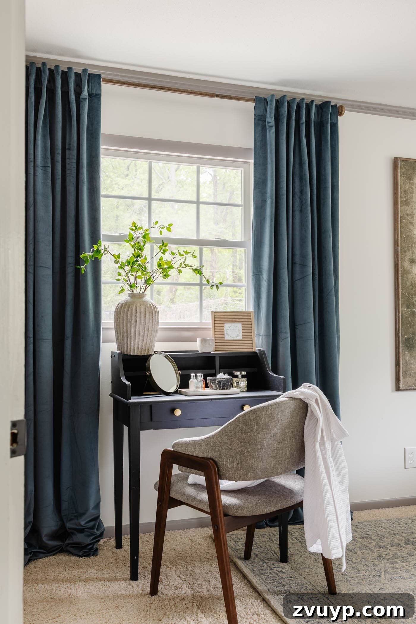 Parisian Chic on a Shoestring Budget 7 A chic bedroom featuring a black writing desk/vanity, complemented by luxurious blue velvet curtains that add a pop of jewel-toned elegance to the space.