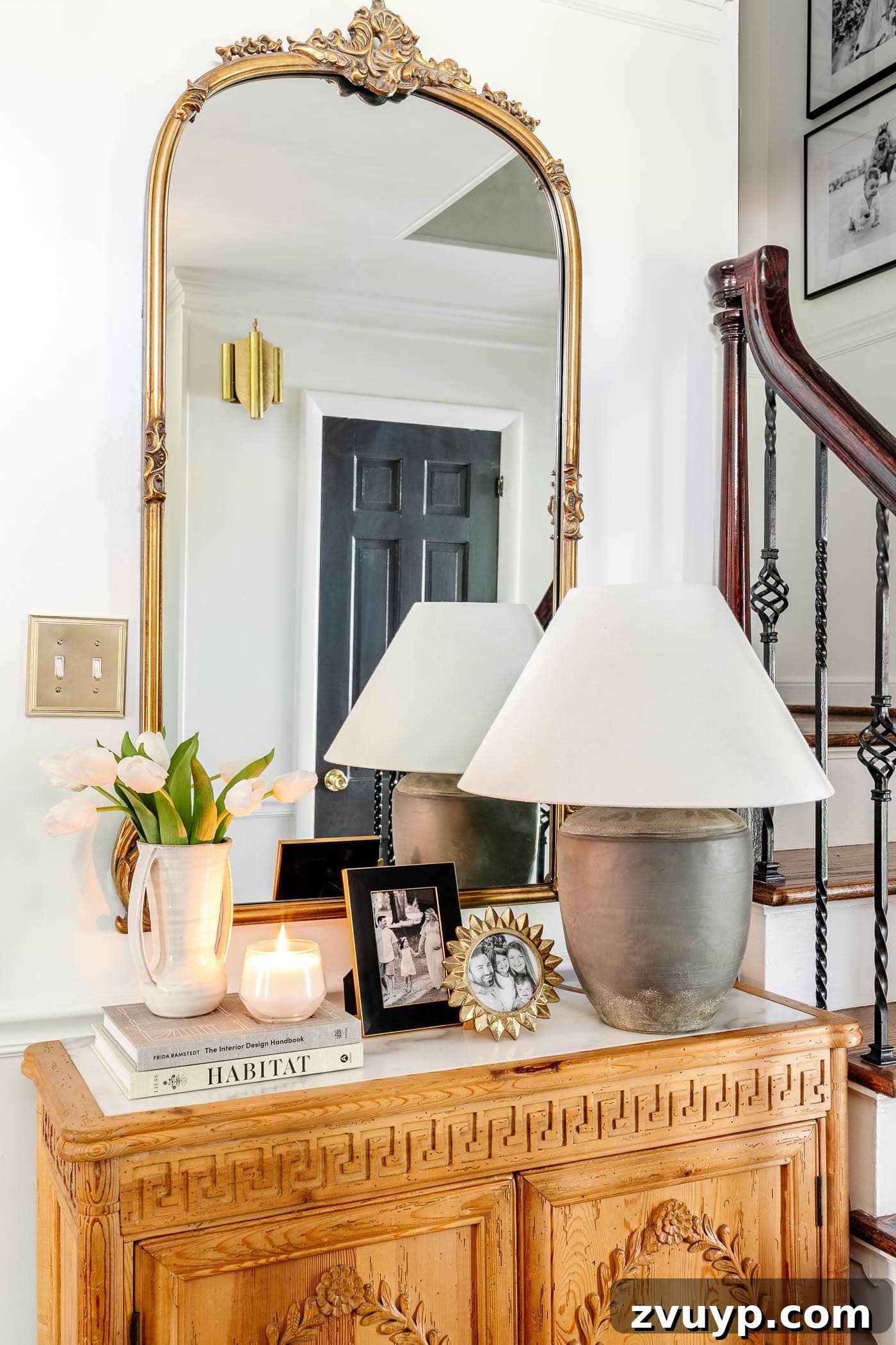 Parisian Chic on a Shoestring Budget 10 A magnificent gilded mirror serving as an elegant focal point in an entryway, beautifully complemented by a wooden and marble accent chest, exuding Parisian charm.