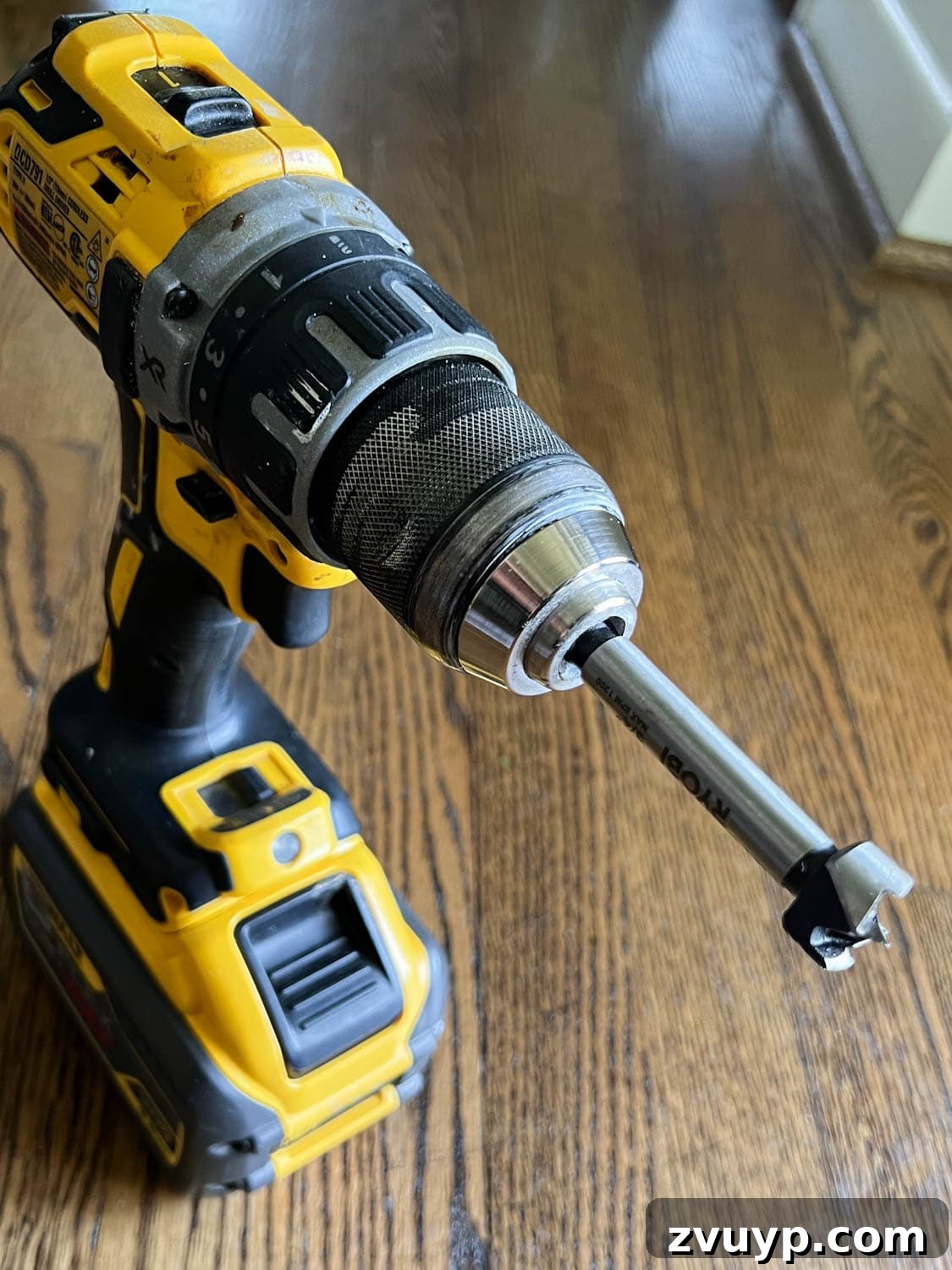 DIY Stair Spindle Swap For A Modern Makeover 11 A forstner drill bit being used on a drill to remove old adhesive from stair treads