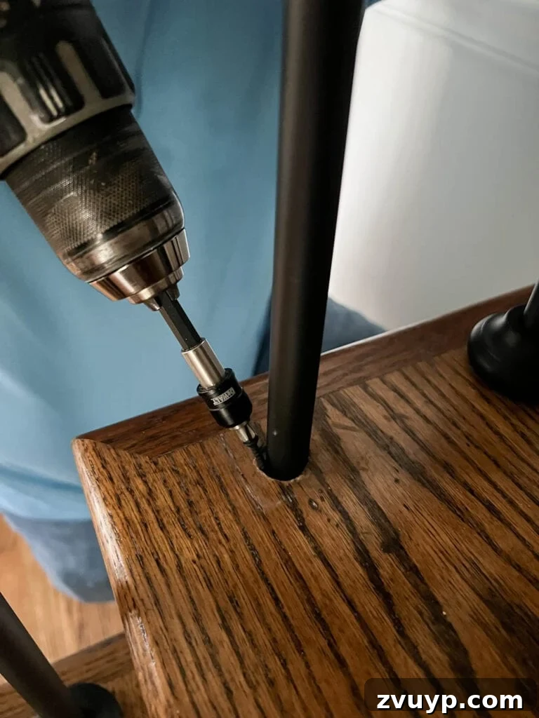 DIY Stair Spindle Swap For A Modern Makeover 28 Drilling a screw into a stair tread to securely anchor a stair baluster