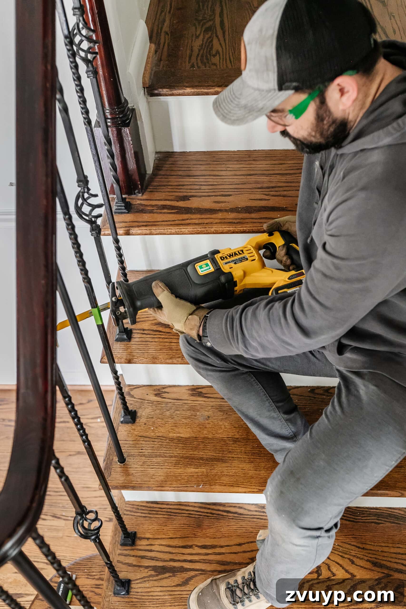 DIY Stair Spindle Swap For A Modern Makeover 4 A person using a reciprocating saw to cut through wrought iron stair spindles