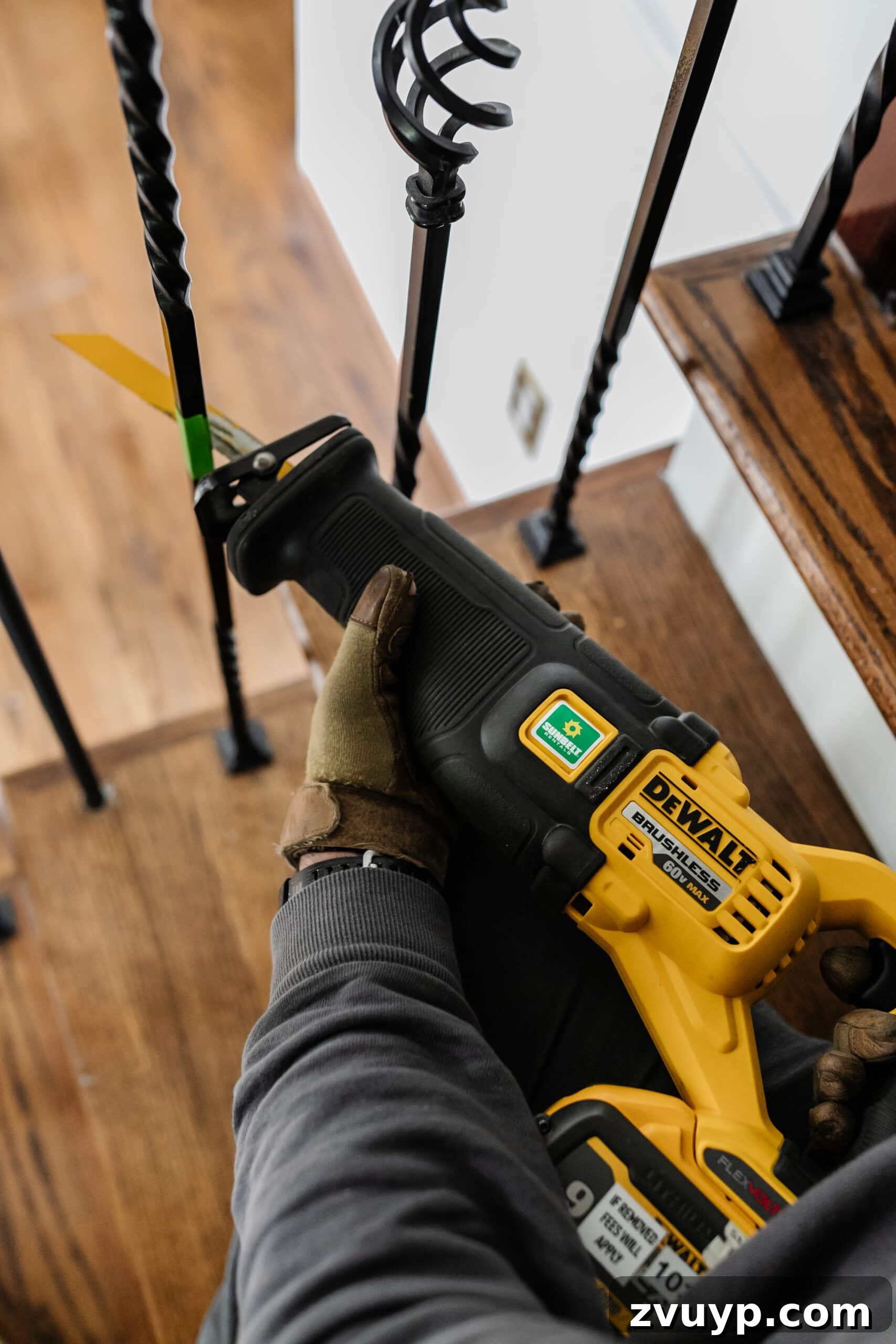 DIY Stair Spindle Swap For A Modern Makeover 7 Close-up of a person cutting wrought iron stair balusters with a reciprocating saw, demonstrating safe usage