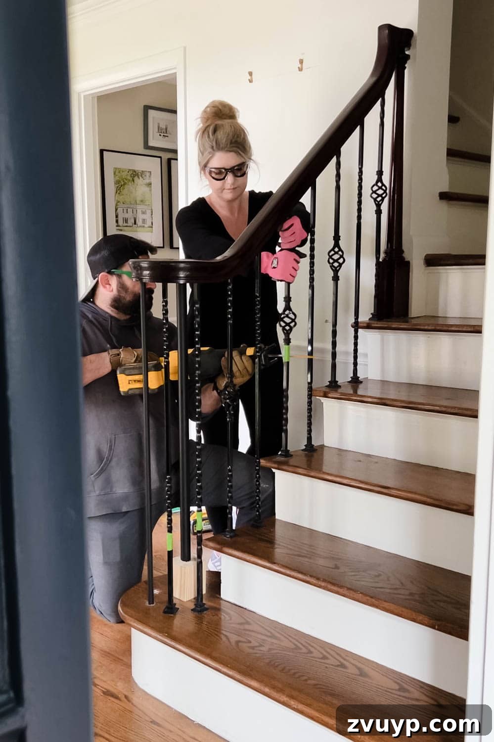 DIY Stair Spindle Swap For A Modern Makeover 8 A couple working together to remove old stair spindles from a railing using a reciprocating saw