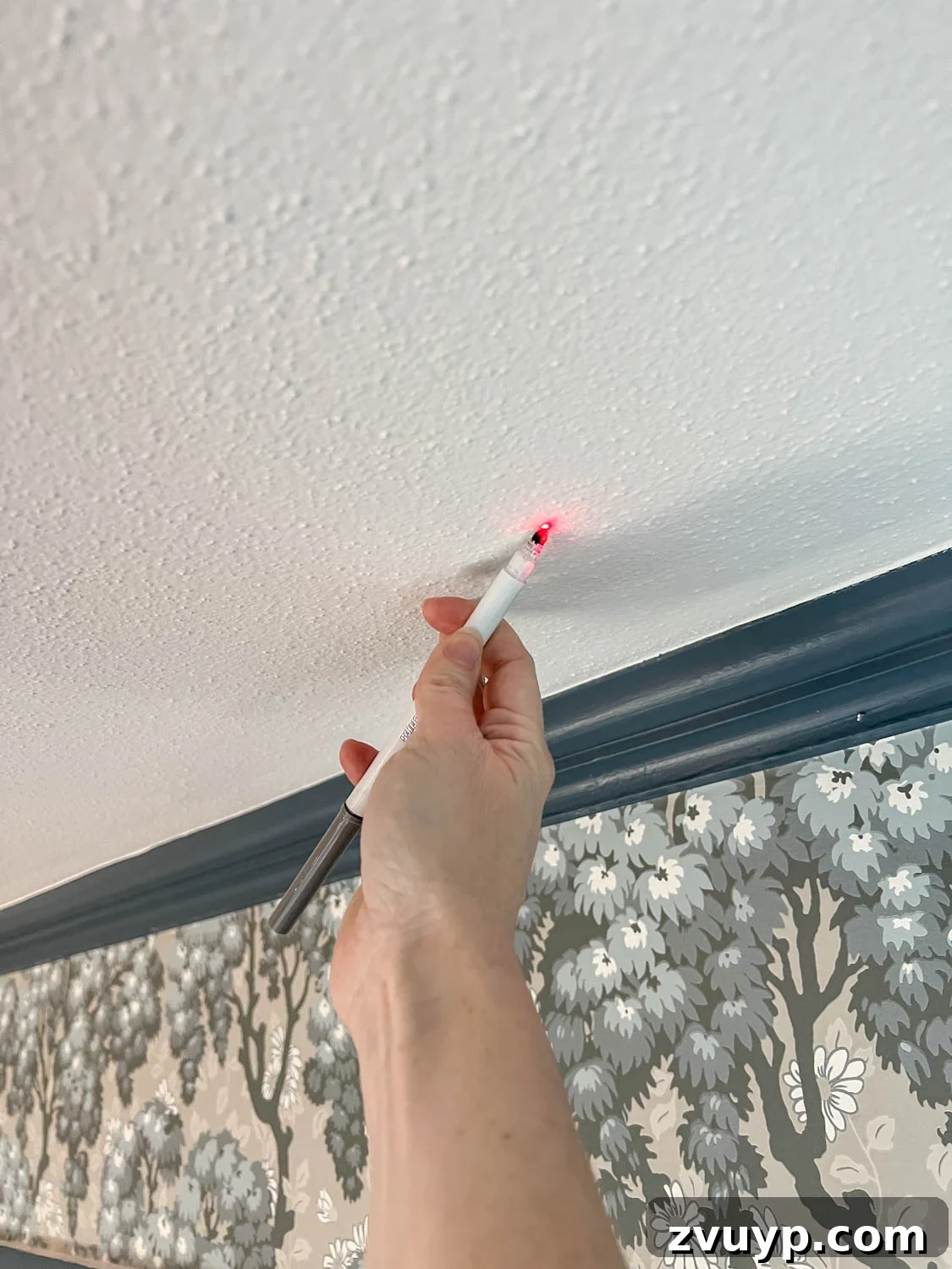 DIY Faux Block Print Ceiling Vinyl Decal Wallpaper 7 Close-up of a laser line guiding the placement of vinyl decals on a textured ceiling, illustrating the accuracy of the marking process.