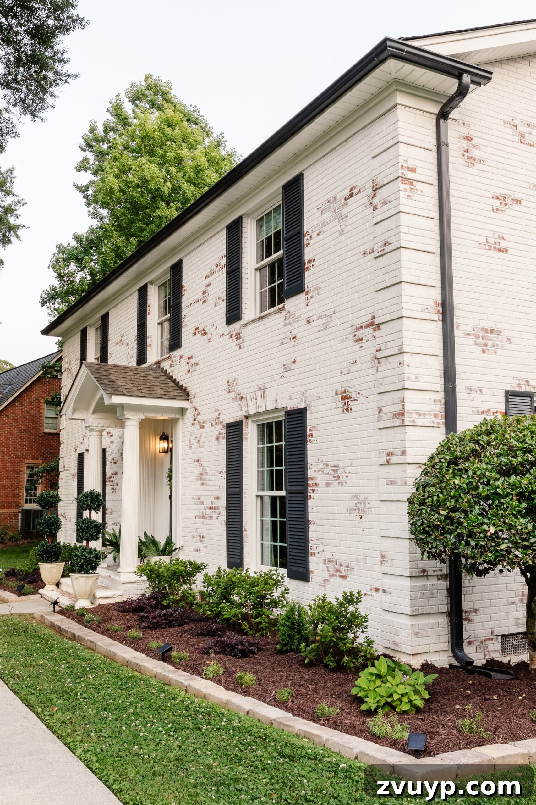 Pristine Limewashed Brick A Comprehensive Care Guide 17 Beautiful limewashed brick colonial house with vibrant flower beds, showcasing a fresh and clean exterior