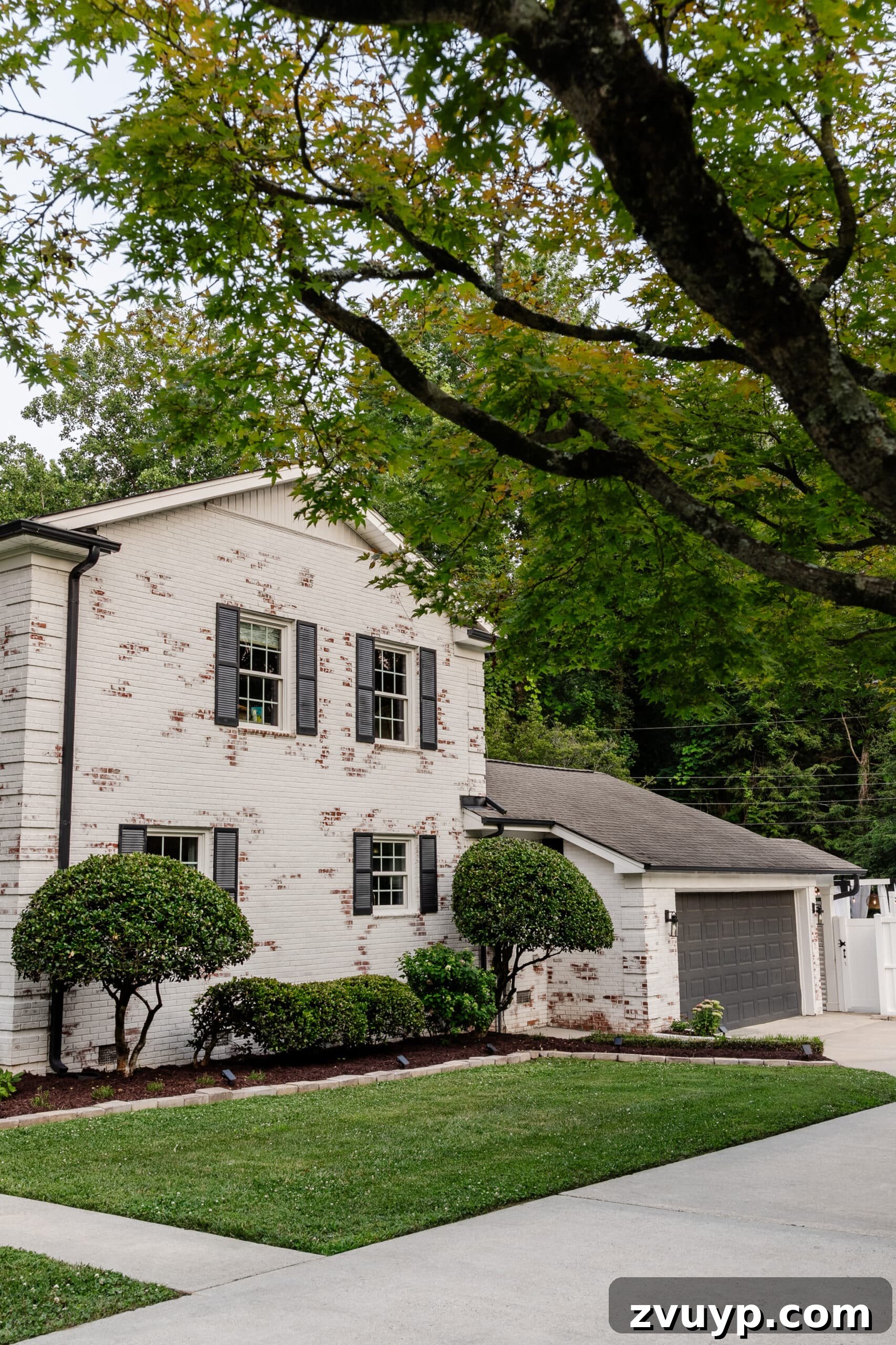 Pristine Limewashed Brick A Comprehensive Care Guide 20 After: White limewashed brick exterior with black gutters, black shutters, and a newly painted black garage door