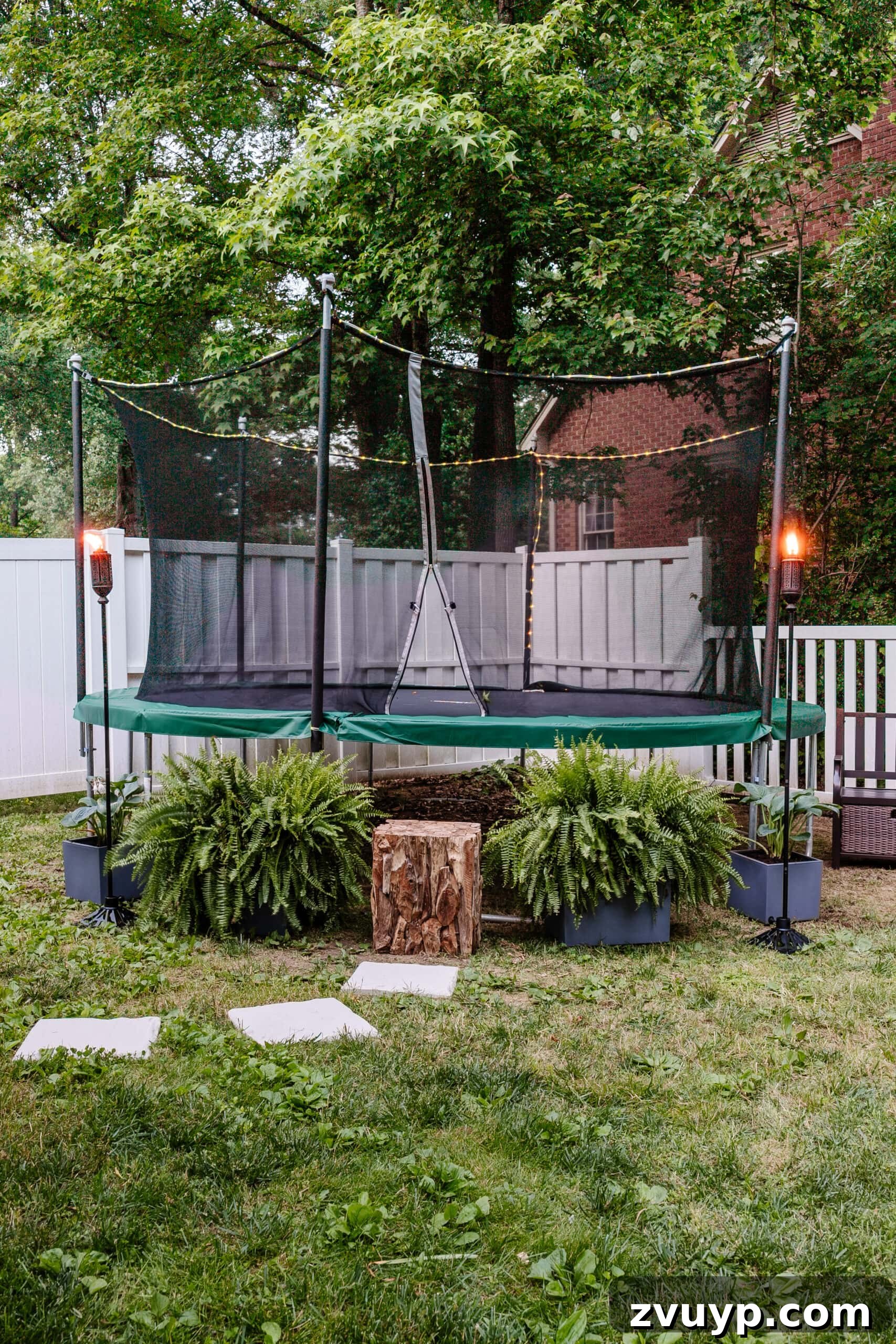 Transform Your Side Yard: 8 Play Area & Trampoline Design Ideas 5 stepping stones leading to outdoor trampoline with tree stump trampoline ladder, ferns, and tiki torches, showcasing lush greenery