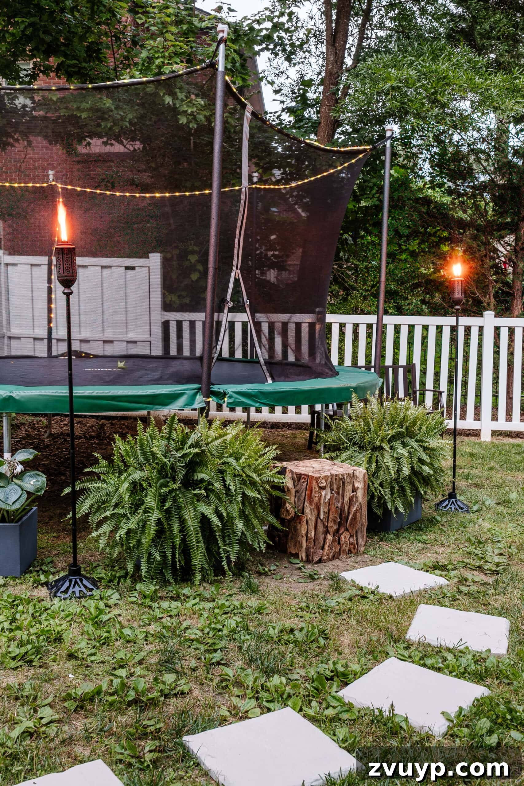 Transform Your Side Yard: 8 Play Area & Trampoline Design Ideas 7 stepping stones leading to outdoor trampoline with tree stump trampoline ladder, ferns, and tiki torches, showcasing the natural step