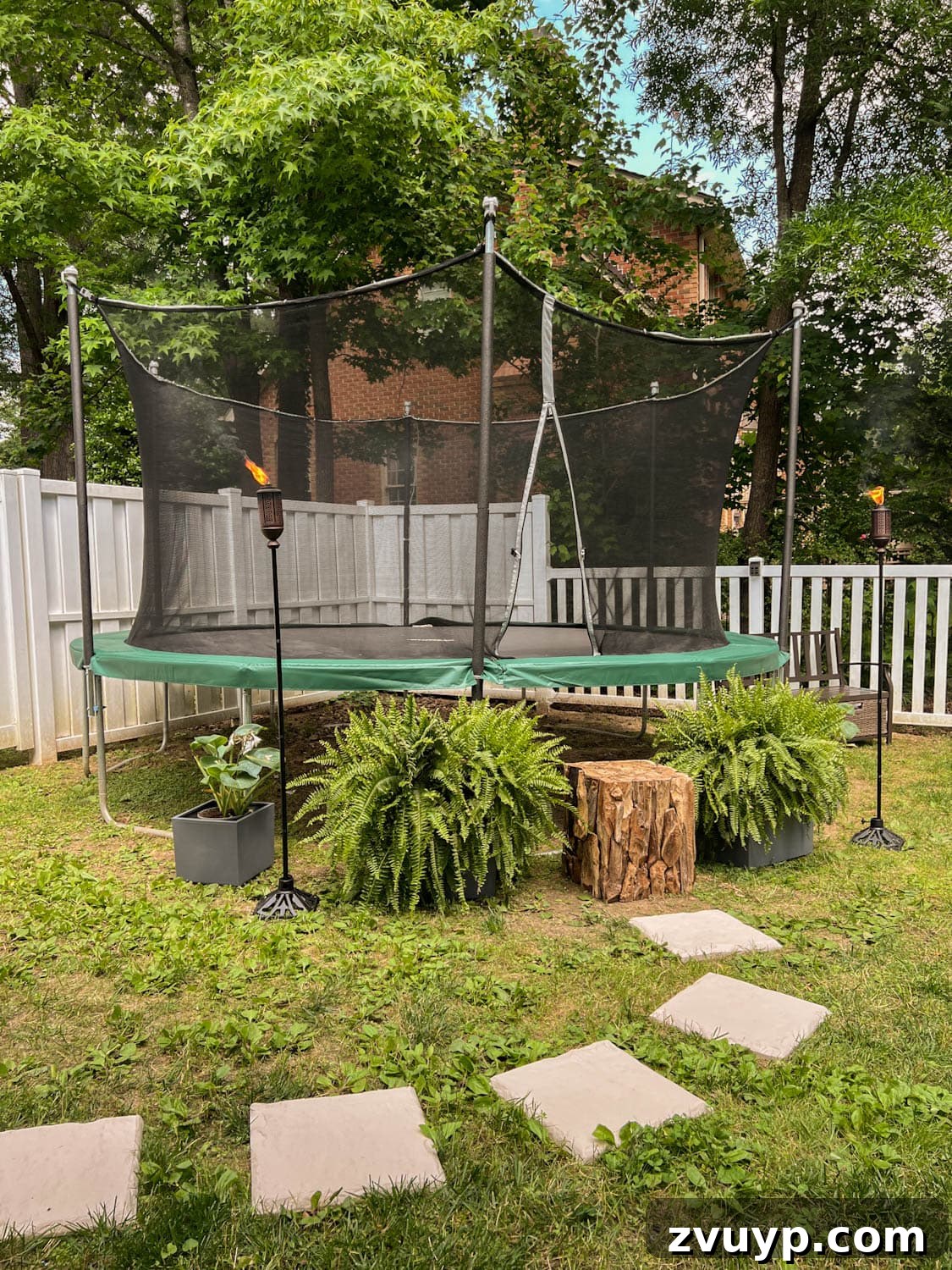 Transform Your Side Yard: 8 Play Area & Trampoline Design Ideas 9 stepping stones leading to outdoor trampoline with tree stump trampoline ladder, ferns, and tiki torches, creating a clean path