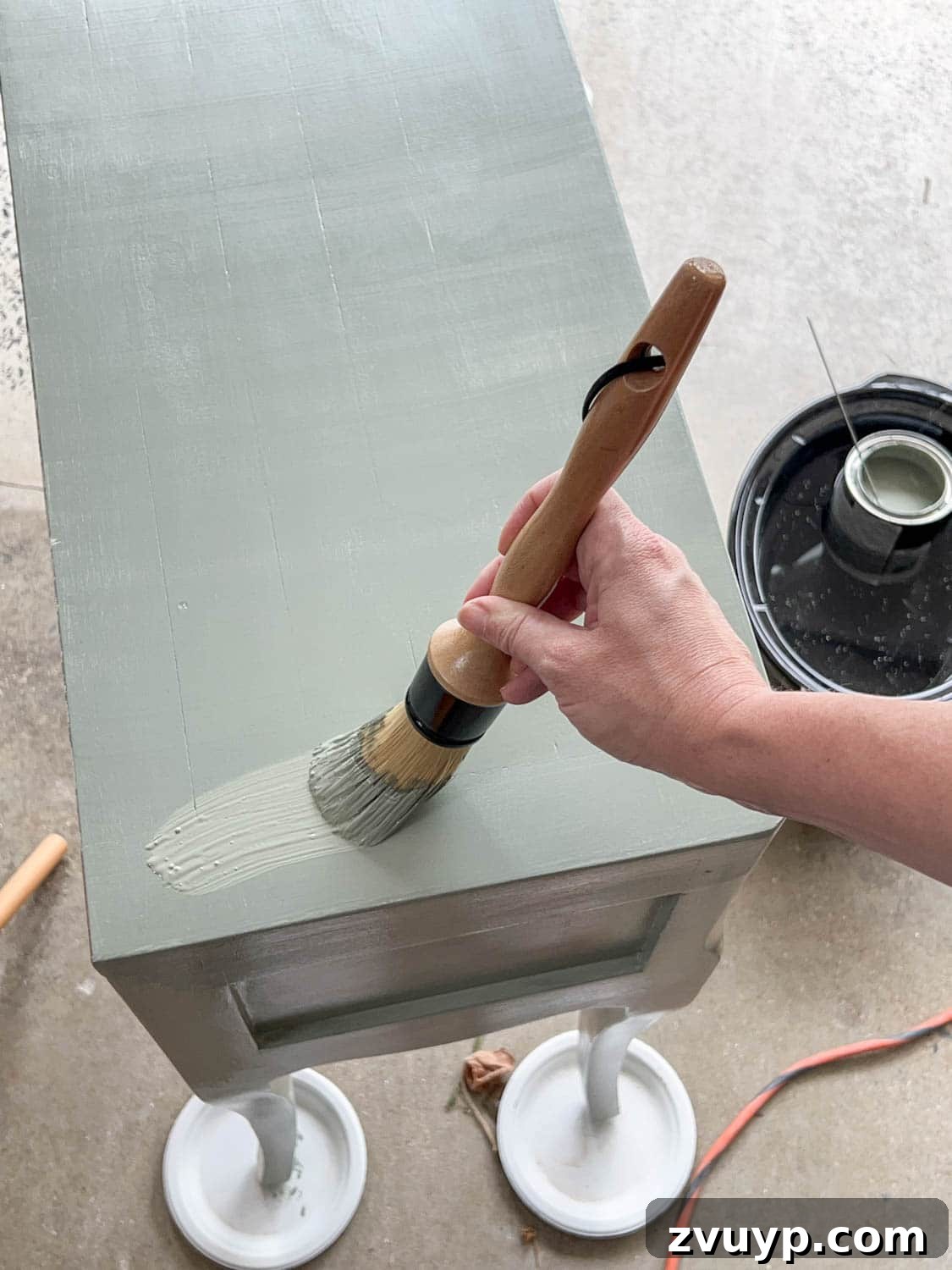 DIY Bedside Table Refresh: Secrets to Smooth Gloss Paint 10 painting a nightstand with Sherwin Williams Evergreen Fog using a round paintbrush for a smooth finish
