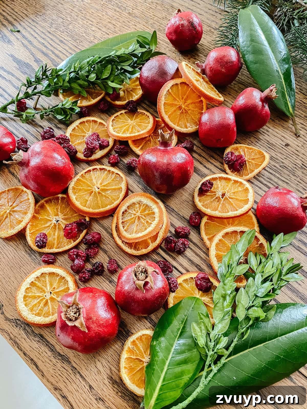 Craft Your Own Stunning Christmas Mantel Garland 16 A collection of beautifully dried orange slices, cranberries, and pomegranates alongside preserved magnolia and boxwood leaves, perfect for Christmas decor.