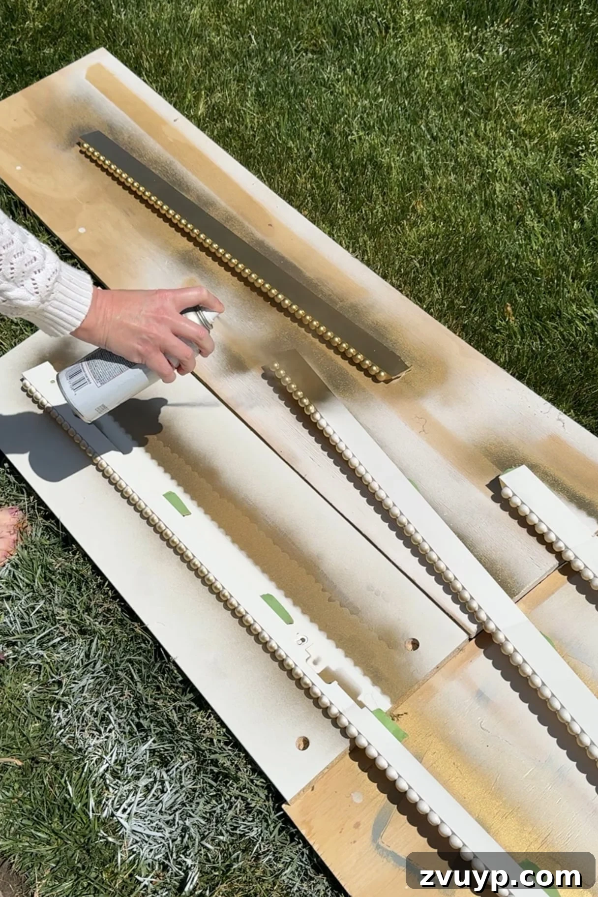 Give Your Samsung Frame TV a Bobbin Frame Makeover 7 Applying gold spray paint to a customized Samsung Frame TV bezel with bobbin details, highlighting the transformation process