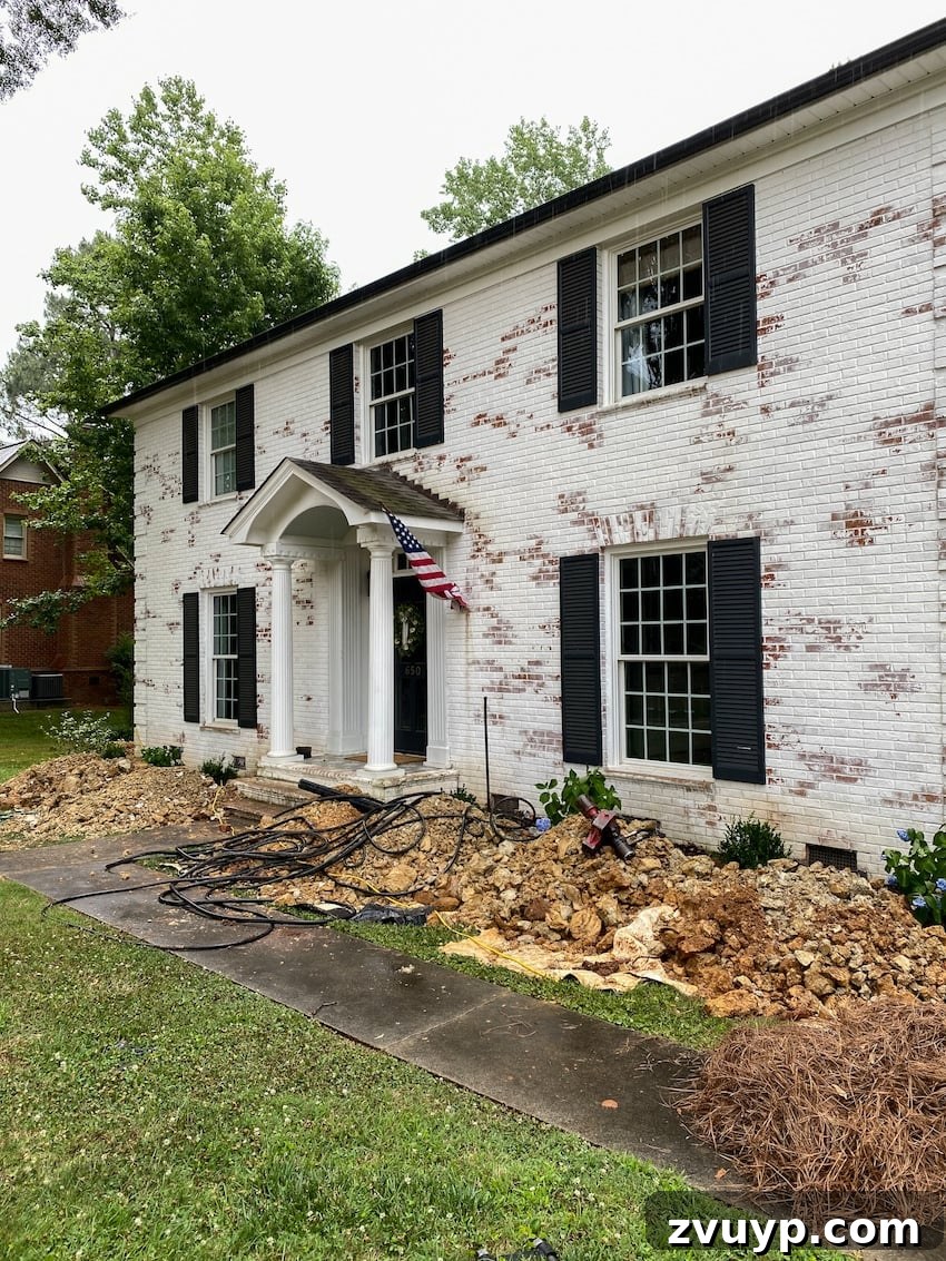 From Patchy to Pristine Our One-Year Front Yard Makeover 5 foundation repairs in front of a brick house with dug up flower beds