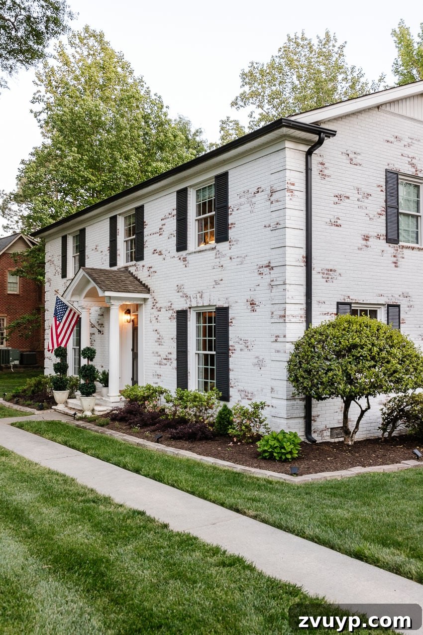 From Patchy to Pristine Our One-Year Front Yard Makeover 6 white limewashed brick house with flower bed makeover and green lawn facelift