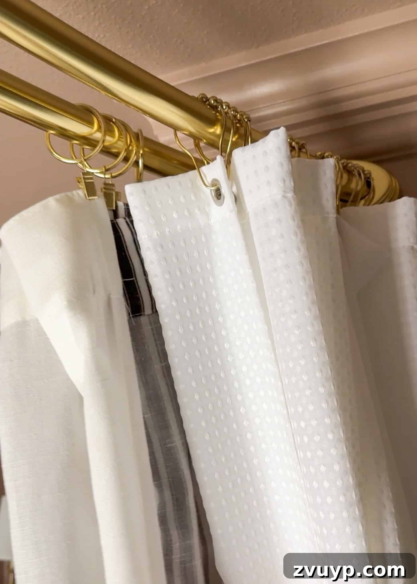 Hang Your Extra Long Shower Curtain Like a Pro 7 A person hanging an extra long shower curtain liner on the inside rod of a double shower curtain setup.