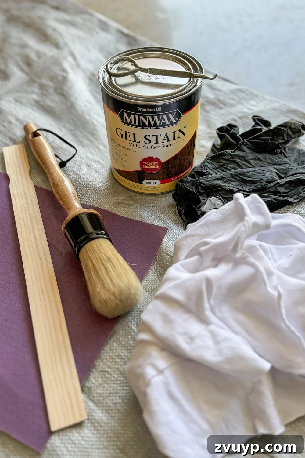 No-Sand Furniture Transformation: Stain Over Stain 4 Collection of supplies for a gel stain furniture makeover, including Minwax Gel Stain, cleaner, sandpaper, rags, brushes, gloves, and polycrylic
