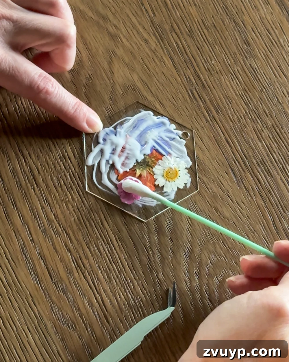 Surprisingly Simple Pressed Flower Ornaments 7 A craft brush applying a thin layer of Mod Podge over pressed flowers on an acrylic tag, sealing the DIY ornament and giving it a matte finish.