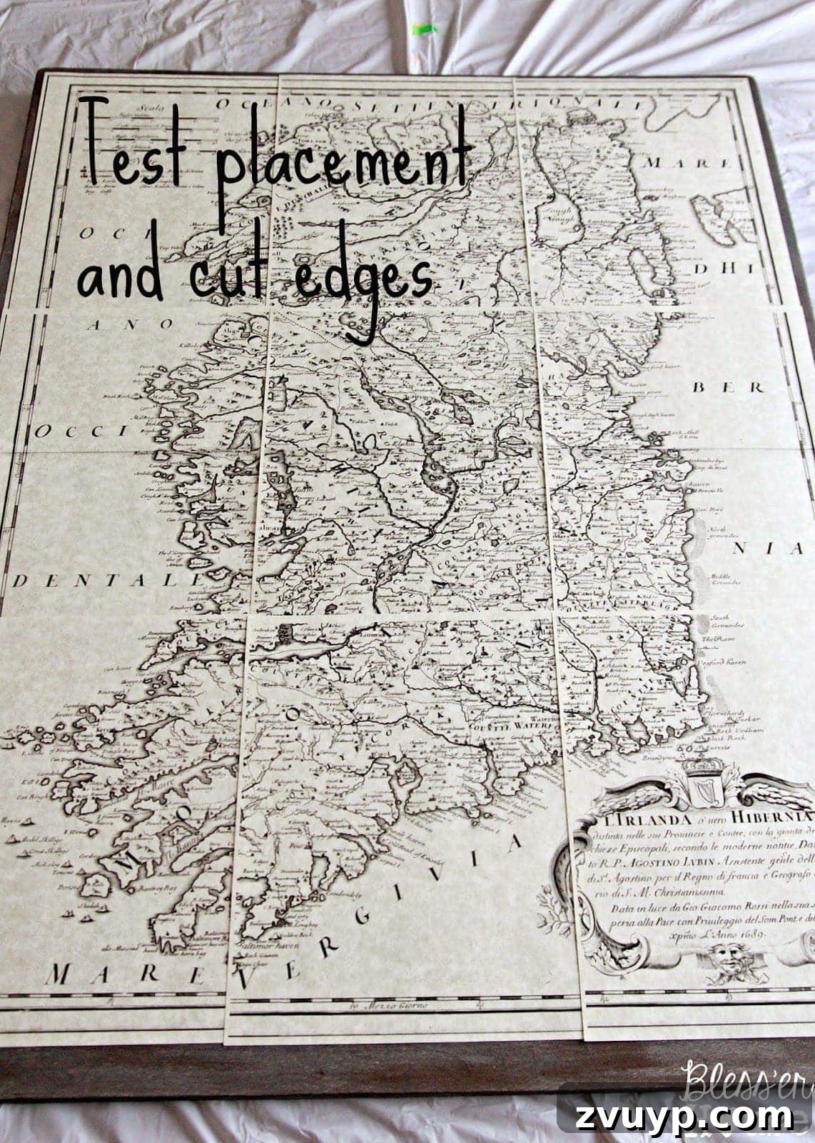 Printed map pages laid out on stained plywood to determine placement and border.