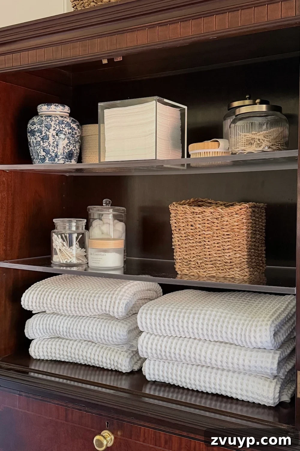 Secretary Desk Transformation: DIY Makeup Vanity for Small Bathrooms 6 Secretary desk upper cabinet open, showcasing neatly folded towels and apothecary jars for organized bathroom essentials
